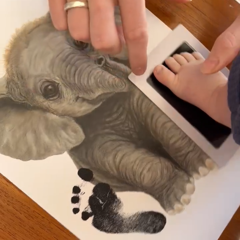 A baby's footprint being added to an Elephant print using ink pads